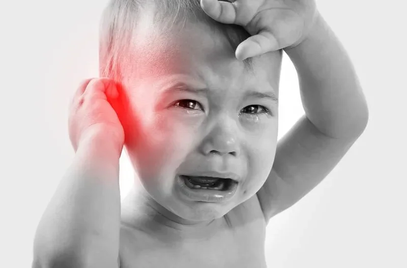 Infant showing signs of ear infection, seeking comfort
